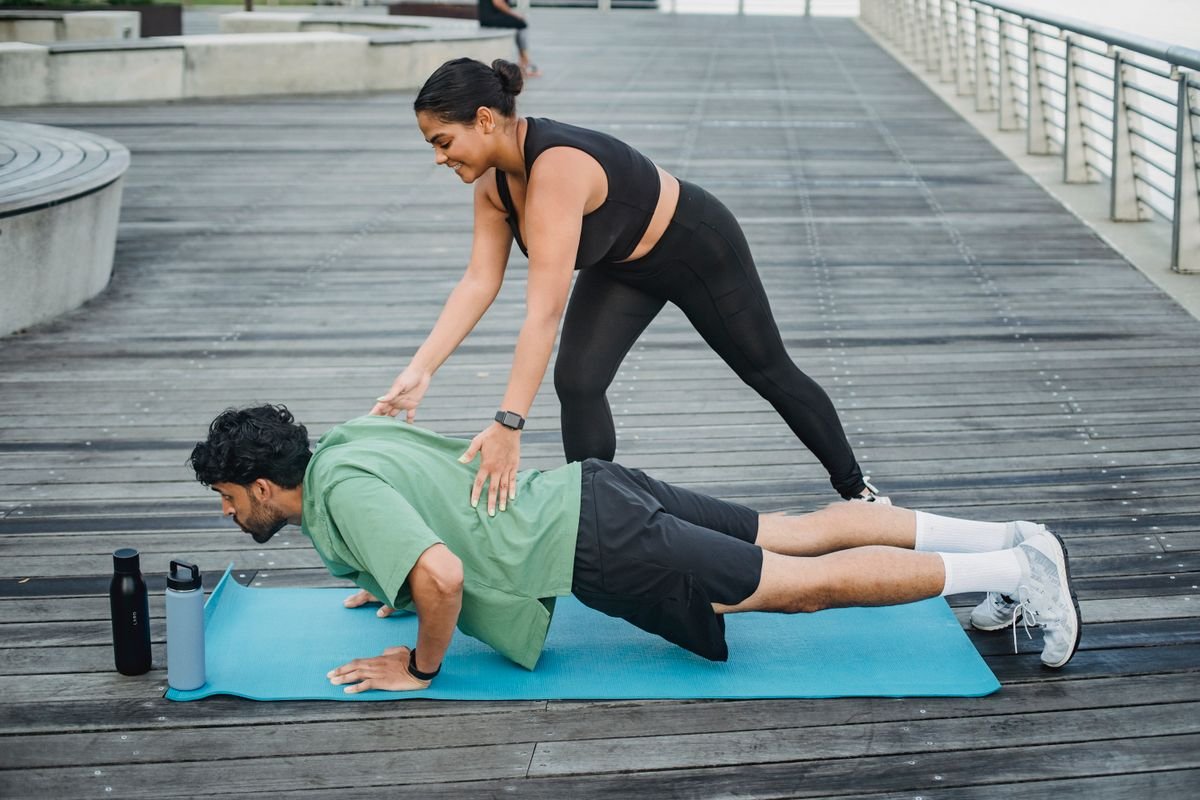 Une coach corrige la position d'un participant pendant des pompes